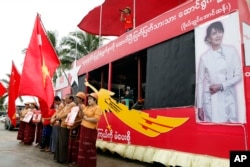 FILE - Supporters holding flags of Myanmar's opposition leader Aung San Suu Kyi's National League for Democracy party stand as a Myanmar artist sings a song on campaign truck during an election campaign in Yangon, Oct. 7, 2015.