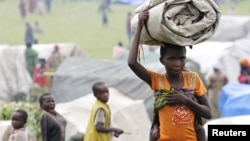 A newly arrived refugee from the Democratic Republic of Congo carries her belongings at a makeshift refugee camp at Bunagana near Kisoro town in Uganda, May 15, 2012. 