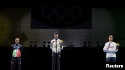 香港劍擊選手張家朗（圖中）2021年7月26日在東京奧運會上奪得男子花劍個人賽金牌後，與銀牌和銅牌得主分別站在頒獎台上 （路透社照片）