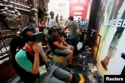 FILE - Attendees wearing Oculus Rift virtual reality headsets view a 3-dimensional video for the "Pacific Rim: Jaeger Pilot" video game during the 2014 Comic-Con International Convention in San Diego, California, July 25, 2014.