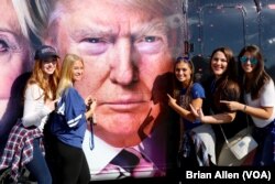 Hofstra University students pose with Donald Trump's likeness on the side of a bus. Trump will take on Hillary Clinton in an on-campus debate on Monday night. (B. Allen/VOA)