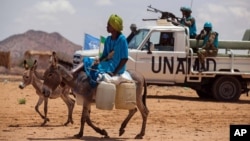 Un homme, monté sur un ane, dépasse un convoi de la mission des Nations unies dans le sud du Darfour, Soudan, le 30 juin 2014