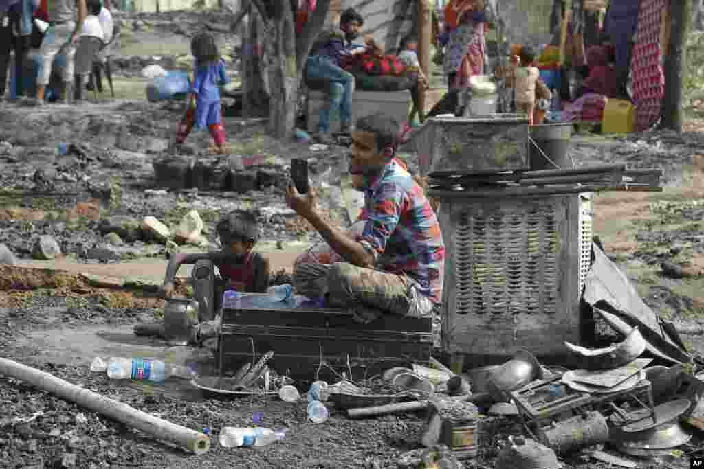 A man makes a video call to his relatives after a fire at a slum area on the outskirts of Jammu, India.