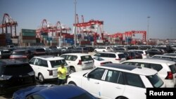 FILE - A worker inspects imported cars at a port in Qingdao, Shandong province, China, May 23, 2018.
