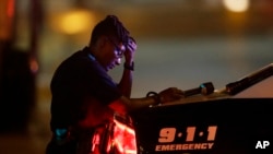 A Dallas police officer, who did not want to be identified, takes a moment as she guards an intersection in the early morning after a shooting in downtown Dallas, July 8, 2016.