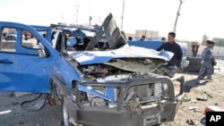 A policeman looks at a damaged police vehicle following a car bomb and minutes later a suicide bombing targeting the provincial headquarters in the western Iraqi city of Ramadi, 27 Dec, 2010.