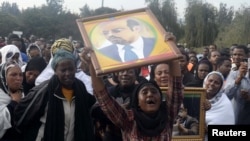 A woman wails while lifting a portrait of the late Ethiopian Prime Minsiter Meles Zenawi as she waits for the arrival of his remains in the capital Addis Ababa, August 21, 2012. 