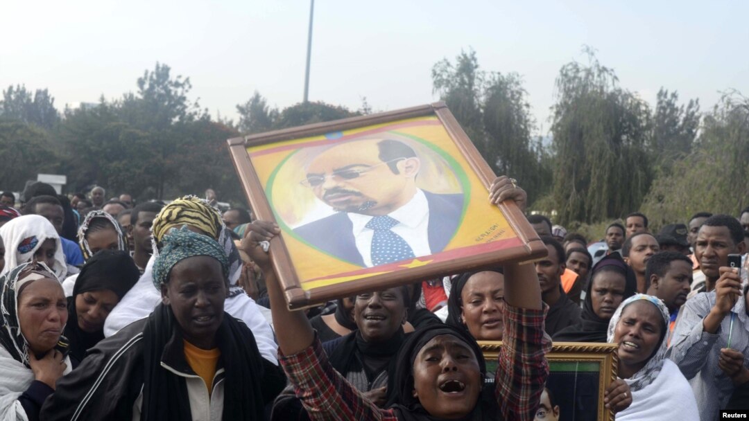 A woman wails while lifting a portrait of Ethiopia's PM Meles Zenawi as she waits for the arrival of his remains in Ethiopia's capital Addis Ababa, August 21, 2012.