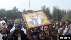 A woman wails while lifting a portrait of Ethiopia's PM Meles Zenawi as she waits for the arrival of his remains in Ethiopia's capital Addis Ababa, August 21, 2012. 