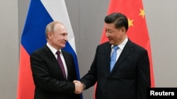 Presiden Rusia Vladimir Putin berjabat tangan dengan Presiden China Xi Jinping selama pertemuan mereka di sela-sela KTT BRICS, di Brasilia, Brazil, 13 November 2019. (Foto: Sputnik/Ramil Sitdikov/Kremlin via REUTERS)