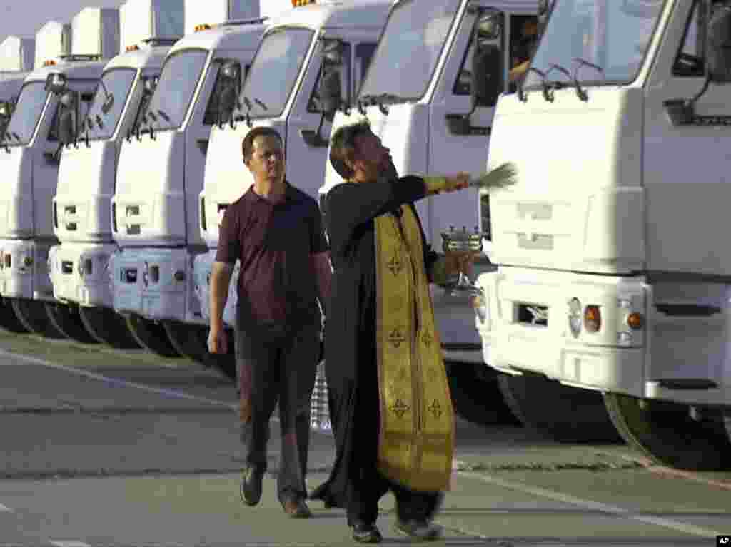 A Russian Orthodox Church clergyman blesses a convoy of white trucks with humanitarian aid in Alabino, outside Moscow, Tuesday, Aug. 12, 2014
