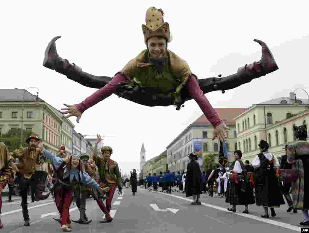 독일 남부 뮌휀에서 열린 옥토버르페스트 맥주 축제에서 전통의상 퍼레이드가 열린 가운데, 광대 복장을 한 남성이 점프하고 있다.