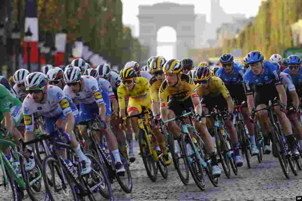 Slovenia&#39;s Tadej Pogacar, wearing the overall leader&#39;s yellow jersey, center, rides down Champs Elysees with the pack during the twenty-first and last stage of the Tour de France cycling race over 122 kilometers (75.8 miles), from Mantes-la-Jolie to Paris, France.