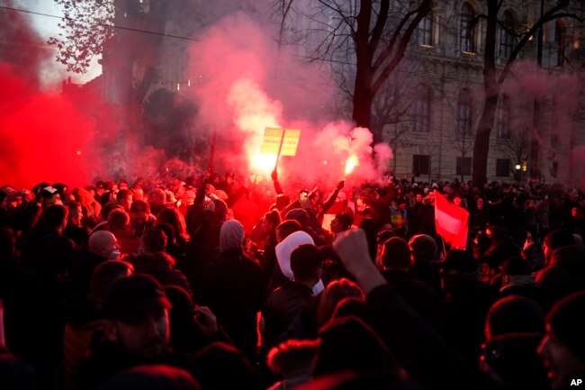 Demonstran meneriakkan slogan-slogan dan suar api selama demonstrasi menentang pembatasan COVID-19 baru di Wina, Austria, 20 November 2021. (Foto: AP)