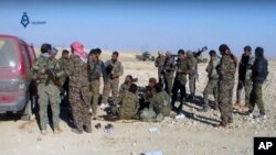 This frame grab from video provided by Qasioun a Syrian opposition media outlet, shows U.S.-backed fighters taking a rest during fighting with the Islamic State group near Ein Issa, north of Raqqa, Syria.