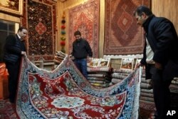 Iranian merchants look at a hand-woven carpet at the Grand Bazaar in Tehran, Feb. 7, 2019.