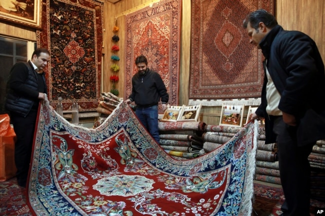 Iranian merchants look at a hand-woven carpet at the Grand Bazaar in Tehran, Feb. 7, 2019.