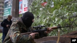 A Pro-Russian gunman aims his weapon behind barricades in Slovyansk, eastern Ukraine, on May 2, 2014.