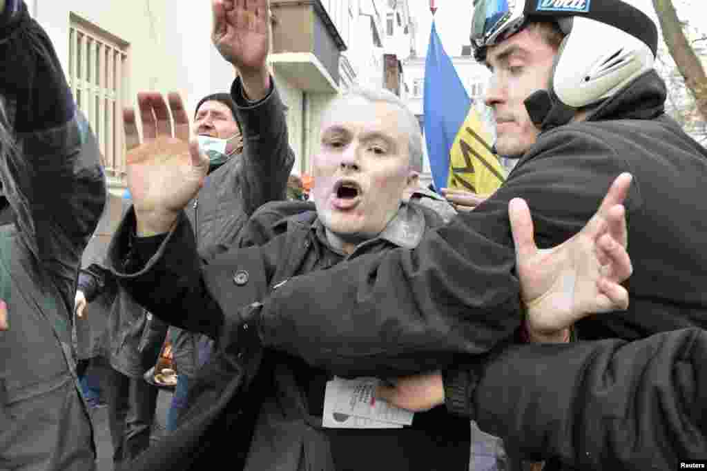 Manifestantes escoltam um homem não identificado depois de atacarem o edifício do Partido das Regiões, Kiev, Fev. 18, 2014. 
