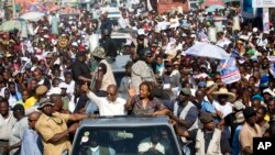 FILE -- Haiti's former President Jean-Bertrand Aristide, left, waves to supporters as he campaigns with presidential candidate Maryse Narcisse, of the Fanmi Lavalas political party, in Port-au-Prince, Haiti, in mid-September. Haiti will hold elections on 