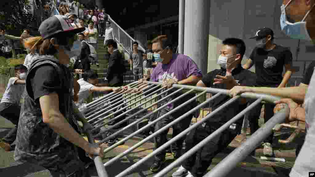 Des hommes portant des masques enlèvent des barricades métalliques que des manifestants ont érigées pour bloquer la rue principale près de &nbsp;centre du district économique de Hong Kong, lundi, le 13 octobre 2014. (AP Photo/Vincent Yu) 