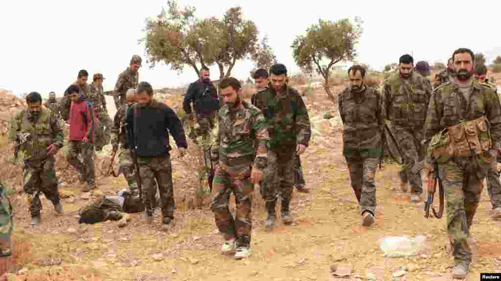 Forces loyal to Syria's President Bashar al-Assad carry their weapons and walk in Aleppo's village of Aziza, Nov. 25, 2013.