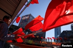FILE - People wave red flags during the filming of a Chinese Communist Party propaganda video in an upscale shopping district in the Sanlitun area in Beijing, China, Oct. 19, 2021.