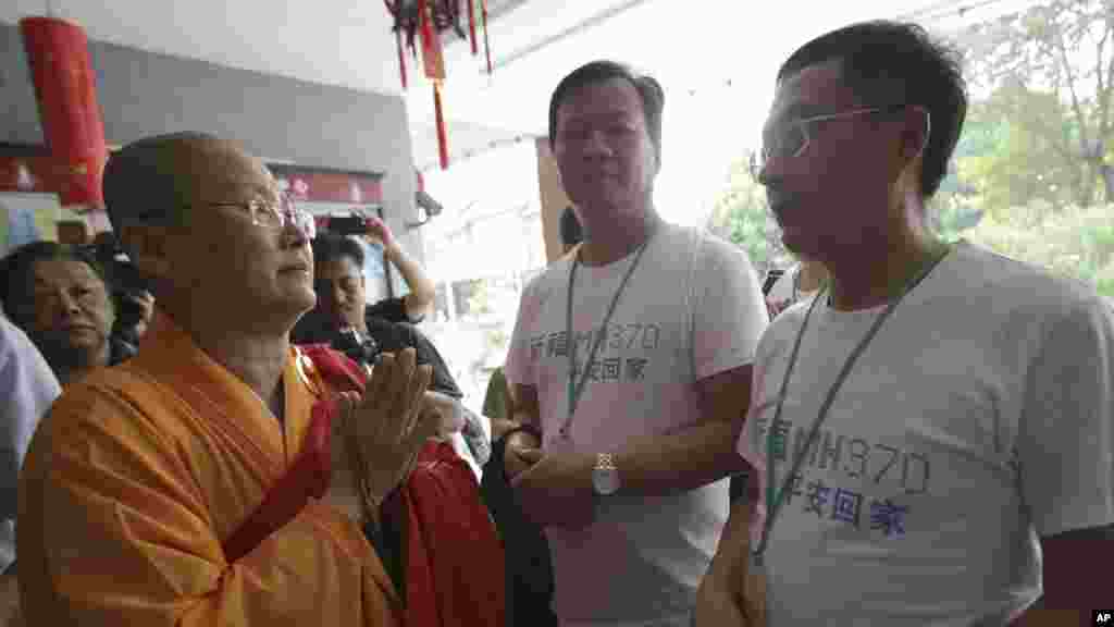 A Buddhist monk welcomes Chinese relatives of passengers on Flight MH370 as they arrive to pray at a Buddhist temple in Petaling Jaya, Malaysia, March 31, 2014.