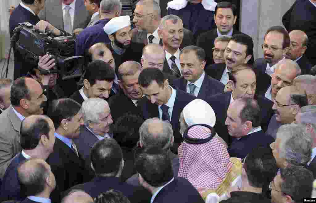 Syria's President Bashar al-Assad (C) chats with people after prayers for Eid al-Adha at al-Afram Mosque, Damascus, Syria, October 26, 2012.