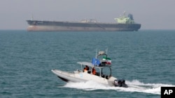 In this July 2, 2012 file photo, an Iranian Revolutionary Guard speedboat moves in the Persian Gulf while an oil tanker is seen in background. (AP Photo/Vahid Salemi, File)