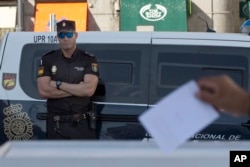 A national police officer watches a person casts a symbolic 'No' vote during protest against the Catalonian referendum in Madrid, Spain, Sept. 29, 2017.