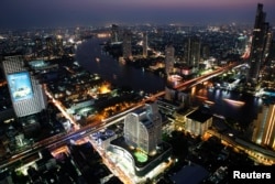 FILE - Cars and trains move on Taksin bridge over Chao Phraya river in central Bangkok, Thailand, at sunset, March 14, 2013.