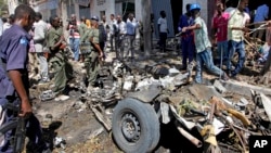 Security forces and others inspect the scene of a car bomb attack in the capital Mogadishu, Somalia Monday, April 11, 2016.