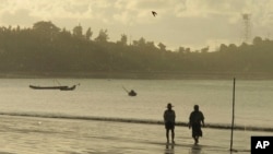 FILE - People walk on a beach in Kyaukpyu on the Bay of Bengal in the Rakhine region, Myanmar, Oct. 5, 2016, where many residents rely on fishing and farming to survive. Residents’ hope that China's big development in the area will bring factories that create jobs.