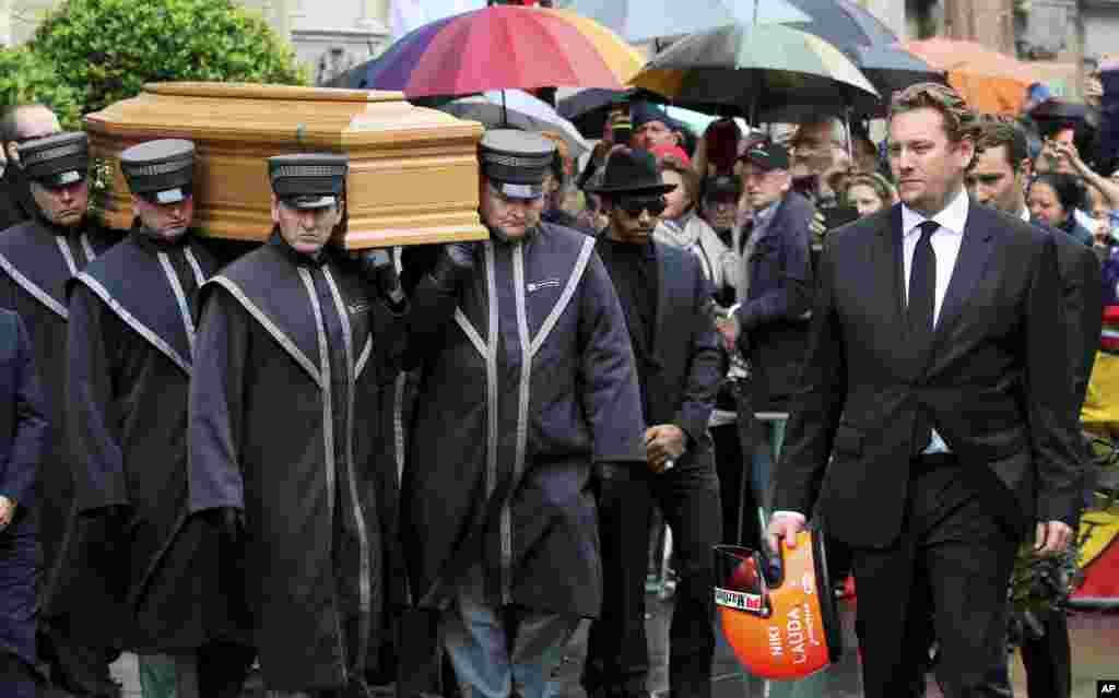 Lukas Lauda, right, holds his father's helmet as he walks in front of the coffin of former Formula One driver Niki Lauda after a funeral service in Vienna, Austria. Three-time Formula One world champion Niki Lauda, who won two of his titles after a horrific crash that left him with serious burns and went on to become a prominent figure in the aviation industry, died last week at the age of 70.
