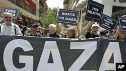 US activists chant slogans as they hold placards after a news conference about an international flotilla to blockaded Gaza, in Athens, June 27, 2011