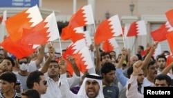 Anti-government protesters shout slogans while holding Bahraini flags during a protest outside Bahrain's leading opposition party Al Wefaq's headquarters in Manama, May 9, 2012.