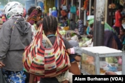 Seorang ibu membawa noken di sebuah pasar di Papua. (Foto: Alam Burhanan/VOA)