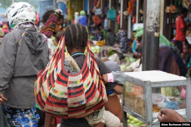 Seorang ibu membawa noken di sebuah pasar di Papua. (Foto: Alam Burhanan/VOA)