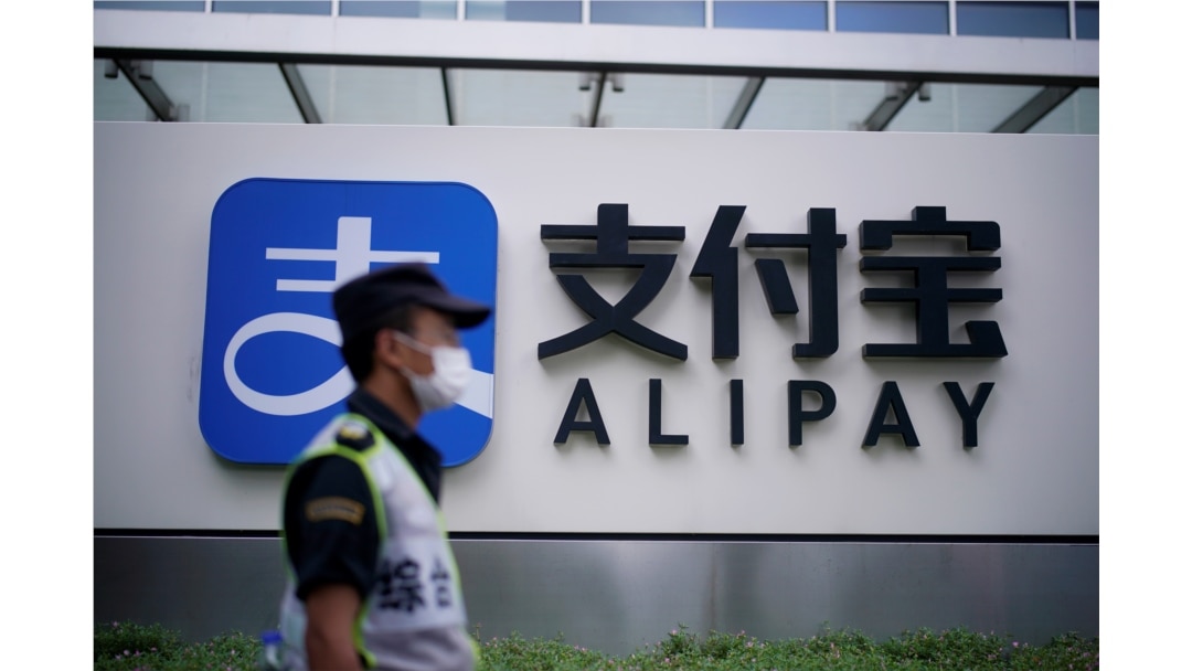 Seorang petugas keamanan melintas di depan logo pembayaran digital Alipay di Shanghai.
