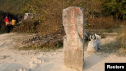 FILE - Chinese business women walk near old border marker 53 between China's Guangxi and Vietnam's Cao Bang province.