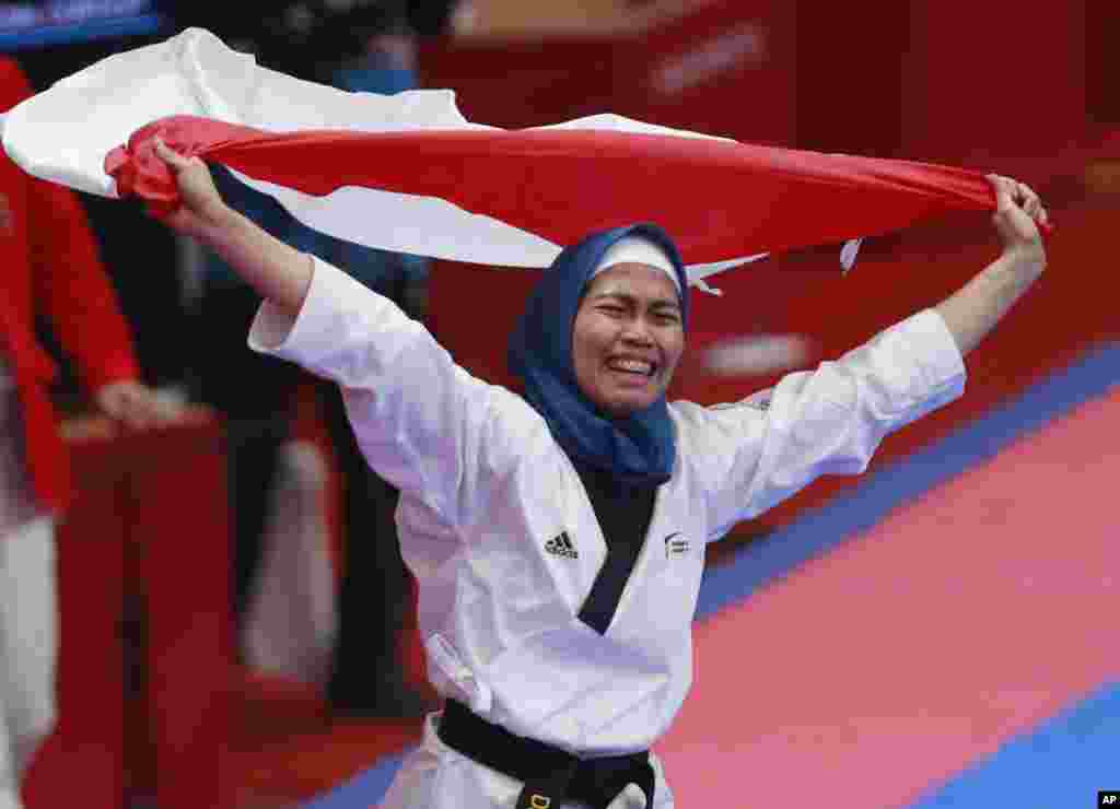 Defia Rosmaniar, merayakan kemenangan dalam final cabang Taekwondo&nbsp;kategori individu poomsae putri pada&nbsp;Asian Games di Jakarta, Minggu 19 Agustus 2018. (AP Photo/Tatan Syuflana)