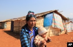An ethnic Shan woman, who was displaced due to fighting between the Myanmar government army and ethnic Shan State Army North (SSA-N) on Oct. 6, 2015, stands in front of a camp for refugees with her grand daughter in Hai Pa village, northeastern Shan state, Feb. 5, 2016.