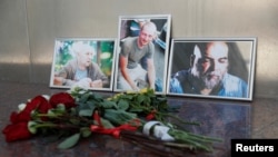 FILE - Photographs of journalists, (R-L) Orhan Dzhemal, Kirill Radchenko and Alexander Rastorguyev, who were recently killed in Central African Republic by unidentified assailants, are on display outside the Central House of Journalists in Moscow, Aug. 1, 2018. 