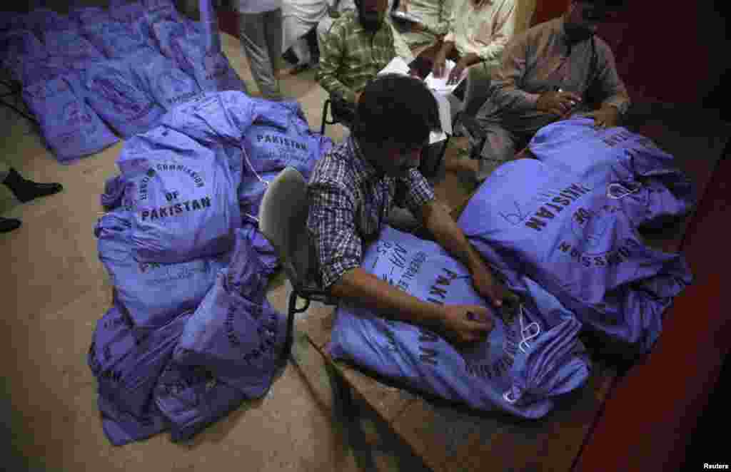 Officials from the Election Commission of Pakistan prepare sacks of stationery materials, before they are transported to polling offices, in the premises of the district city court in Karachi, May 8, 2013. 