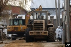 FILE - Workers in protective clothing operate heavy machinery at a sealed-off pig farm after the latest African swine fever outbreak on the outskirts of Beijing, China, Nov. 23, 2018.