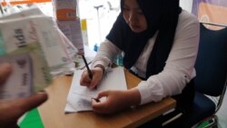 Seorang anggota staf mencatat data KTP pembeli masker di sebuah apotek di Yogyakarta, Sabtu, 14 Maret 2020. (Foto: Nurhadi Sucahyo/VOA)