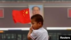 在天安门毛主席像前，小男孩举着中国国旗。在这个小男孩的有生之年，天安门毛像会拆除吗