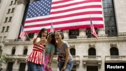 FILE - Chinese tourists take a selfie outside of the New York Stock Exchange, in New York, July 8, 2015.