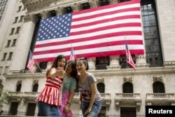 FILE - Chinese tourists take a selfie outside of the New York Stock Exchange, in New York, July 8, 2015.